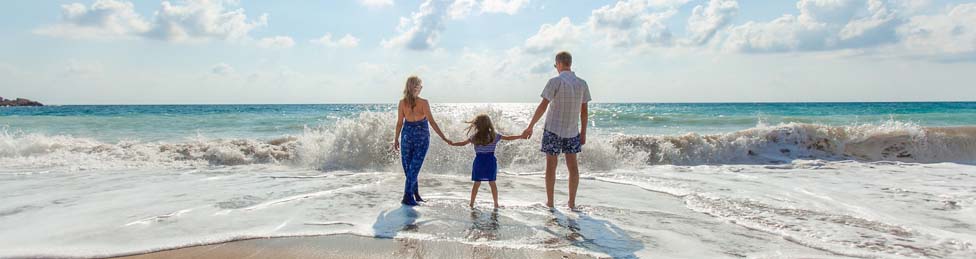 Vater, Mutter, Kind am Meer mit den Füßen im Wasser
